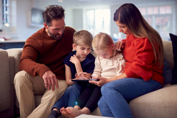 istock Family Sitting On Sofa Watching Digital Tablet Together 1326113683