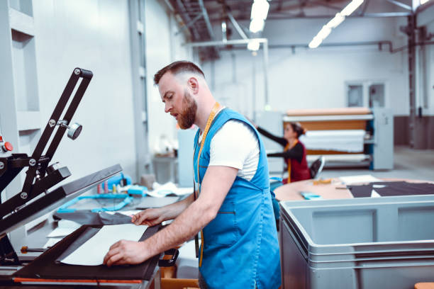 istock Focused Male Worker Printing Cloth Materials In Textile Factory 1326114089