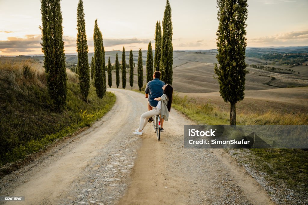 Couple riding on the bicycle Young couple riding a bicycle on a rural road Couple - Relationship Stock Photo