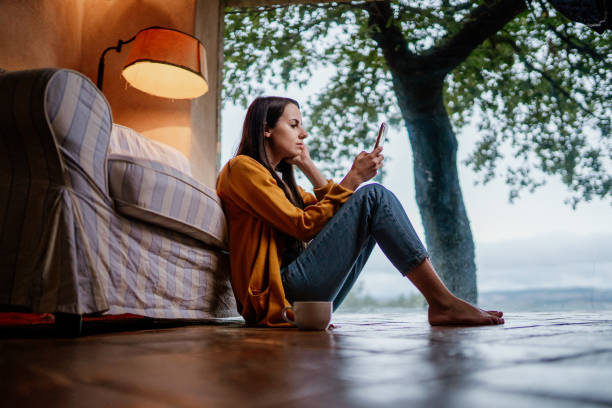 istock Young woman sitting on the floor and using phone 1326115882