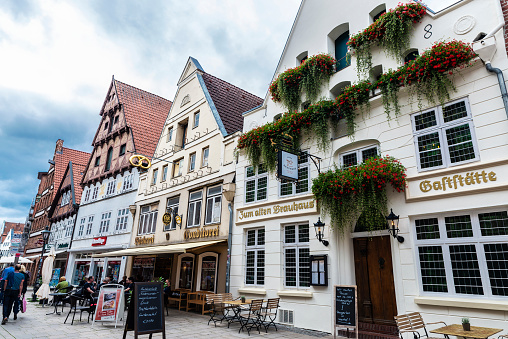Lunenburg, Germany - August 17, 2019: Shopping street with typical town houses, terrace bar, hotel, restaurant, shops and people around in Lunenburg, Lower Saxony, Germany