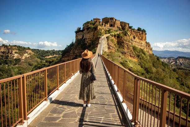 vista traseira de uma jovem em pé em uma ponte, civita di bagnoregio, itália - civita di bagnoregio - fotografias e filmes do acervo