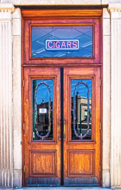 istock Vertical vintage double wooden doors  with transom window with CIGAR sign hanging and old fashioned panels on ceiling visible in classical building 1326119962