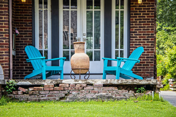 dwa turkusowe krzesła adirondack i chiminea na rozpadającej się ceglanej werandzie w czcionce francuskich drzwi w letni dzień z maleńką amerykańską flagą - flag of oklahoma zdjęcia i obrazy z banku zdjęć