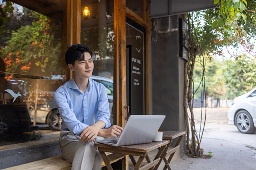 Asian businessmen using laptops in sidewalk cafes