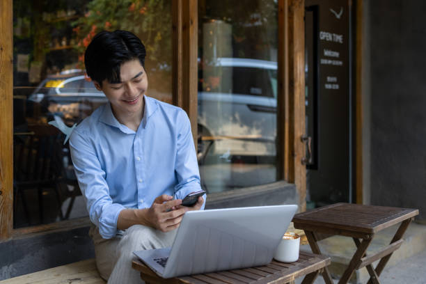 istock Asian businessmen using laptops in sidewalk cafes 1326121705