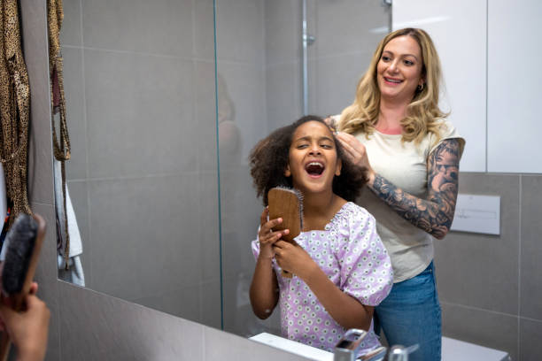 Mother styling daughter's hair at home