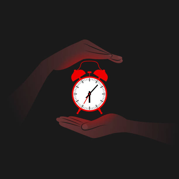 istock Red alarm clock and person's hands near it in darkness 1326126262