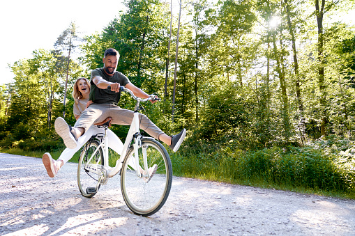 Exuberant couple sharing a bicycle in nature