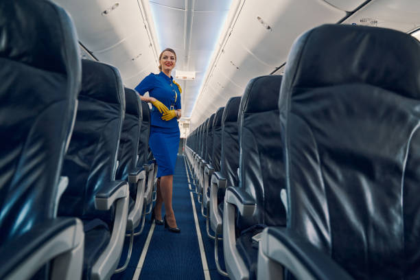 istock Happy attractive flight attendant standing in the cabin aisle 1326132252