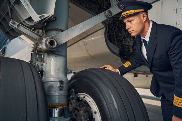 istock Serious focused aviator leaning over the airplane wheels 1326132289