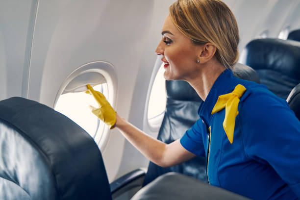 istock Joyous blonde stewardess lowering the blinds on the airplane 1326132294