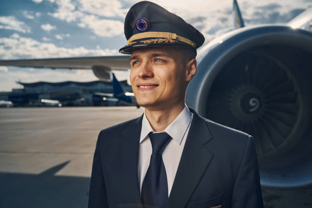 istock Smiling airline pilot in a cap gazing into the distance 1326132337