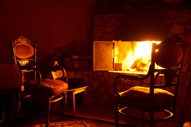 Fireplace with fire and old chairs in a dark room