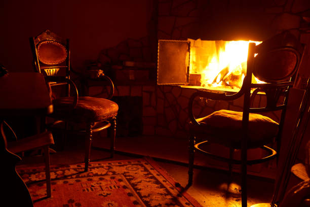 istock Fireplace with fire and old chairs in a dark room 1326134136