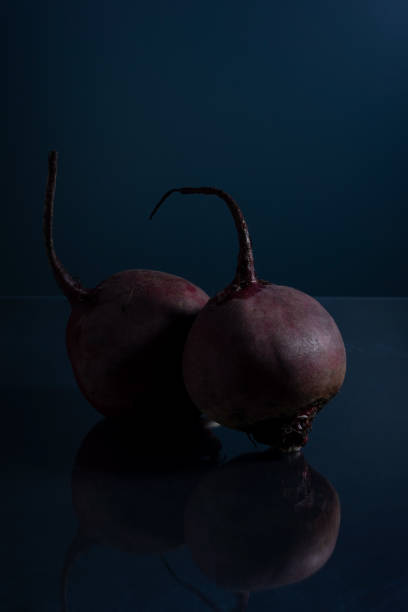 a pair of red beets on a black background minimalistic still life
