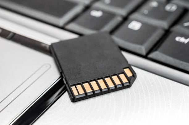 sd memory card on the laptop keyboard. close up. - memory card imagens e fotografias de stock