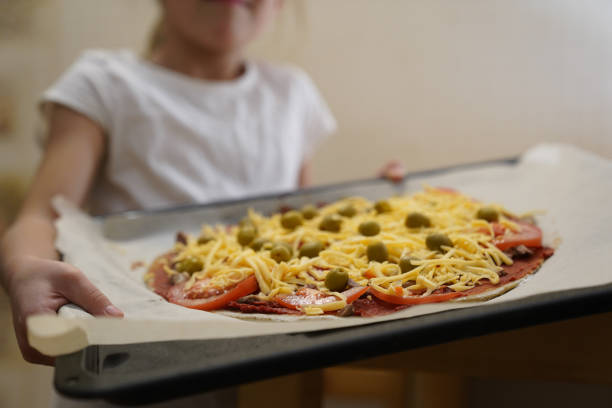 a garota segura uma assadeira preparada para assar pizza com carne. cozimento. - bread food baked 7 grain bread - fotografias e filmes do acervo