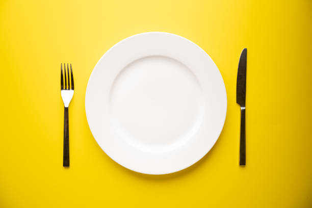 istock knife, fork and plate on yellow background 1326145805