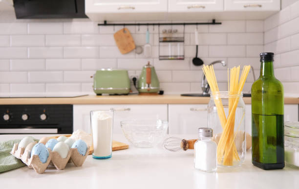istock Stylish white kitchen background with kitchen utensils and green houseplant standing on white countertop, copy space for text, front view 1326146814