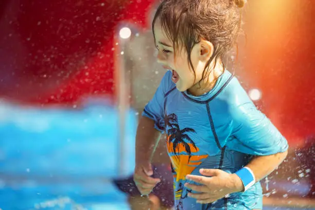 Cheerful Little Boy Having Fun in Waterpark on the Beach Resort. With Pleasure Making Water Splashes. Happy Summer Holidays.