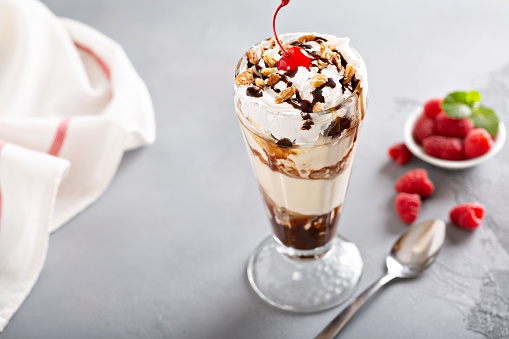 Ice cream, chocolate and whipped cream parfait topped with a cherry