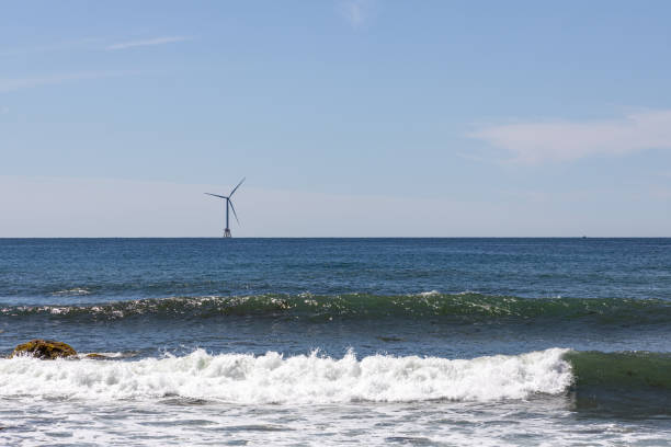 A wind turbine out on the ocean with gentle waves in front