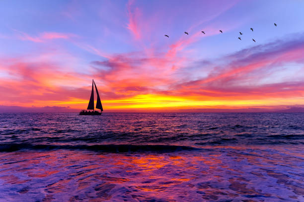 Sunset Ocean landscape Sailboat Silhouette A Sailboat Is Sailing Along The Ocean With A Colorful Sunset on The Ocean Horizon romantic sky stock pictures, royalty-free photos & images