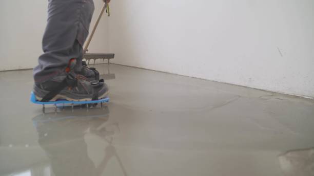 istock A worker rolls out the liquid floor with a trowel. Squeegee for distributing the mixture. The worker levels the liquid floor. Finishing works - Needle roller for bulk floor 1326164349