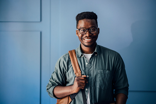 Cheerful African-American man with eyeglasses looking in camera and carrying a backpack