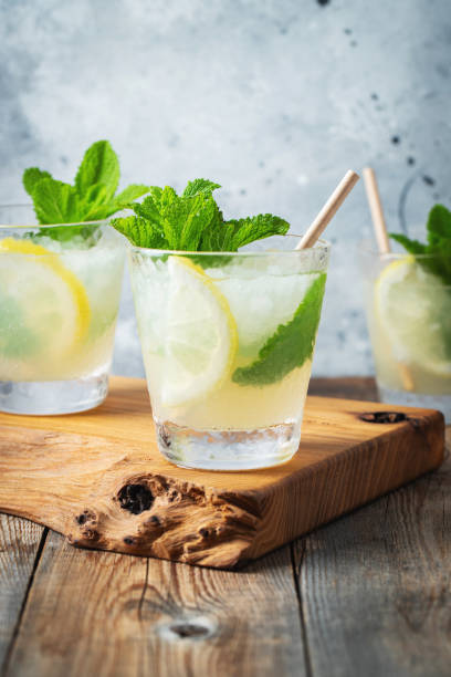 istock Two glass with lemonade or mojito cocktail with lemon and mint, cold refreshing drink or beverage with ice on rustic blue background 1326166365