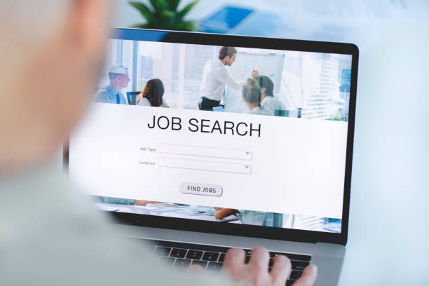 mature businessman looking at job search website on a laptop computer. - job search fotos imagens e fotografias de stock