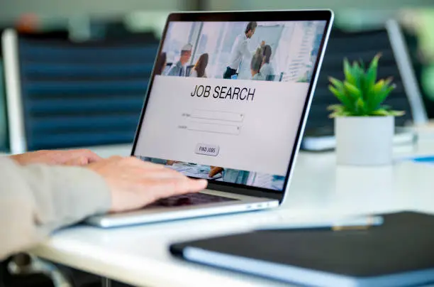 Photo of Mature Businessman looking at job search website on a laptop computer.