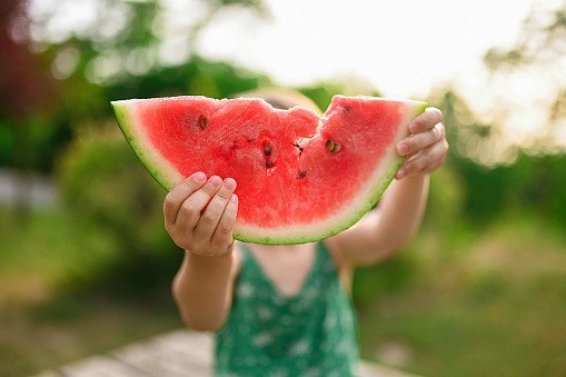 Child holds a slice of watermelon. Selective focus. Image focus technic. Watermelon day concept