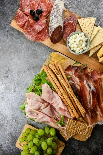 food starter flat lay. Italian appetizers with prosciutto, cheese, snacks on a gray rustic background