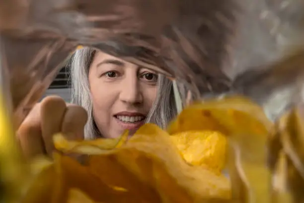 A woman eating chips from a package.
