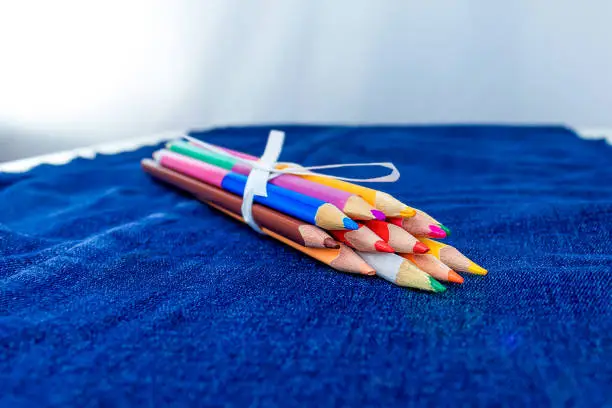 Collection of colored pencils on jeans background. A bunch of pencils.