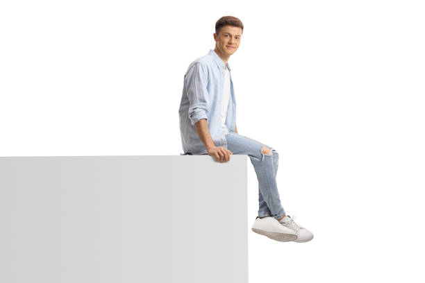 istock Young trendy man sitting on a white wall 1326183284