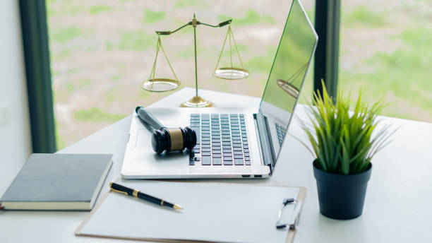 el martillo de un juez descansa sobre una computadora portátil y escamas de oro con papeles y bolígrafos en el escritorio del abogado. - contract signing document legal system fotografías e imágenes de stock