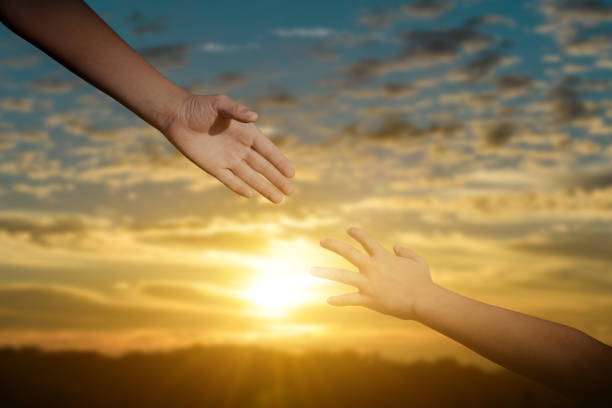 istock Giving a help hand concept. Reaching hand helping, hope and support each other over sunset background 1326186922