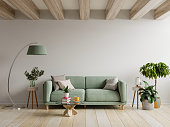 緑のソファは、空の壁と木製のテーブルが付いているモダンなアパートメントのインテリア。