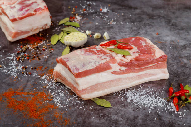 istock Boneless raw pork belly with garlic on dark background. 1326193145