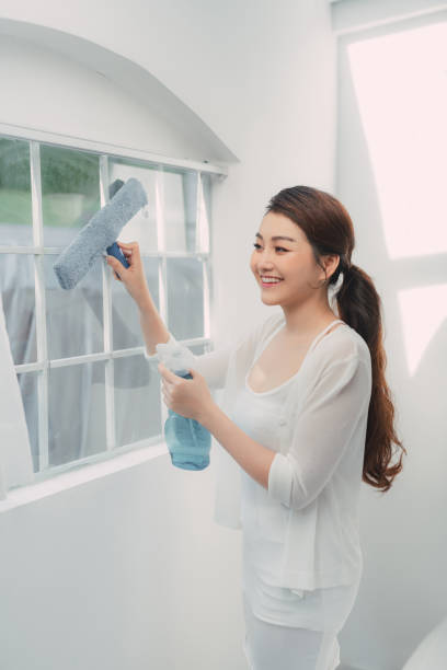 istock Young woman cleaning window at home 1326193956
