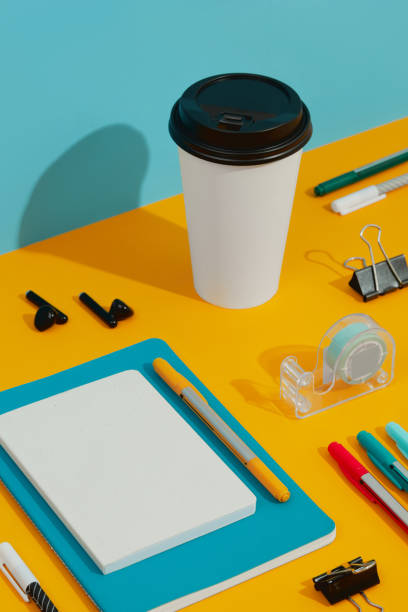 istock Colorful notepads, pens and paper cup on orange table 1326195079