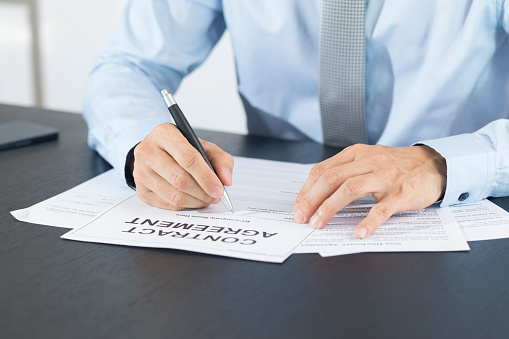 Business man signing document. Business man signing contract. Close up of business manager signing document on table.