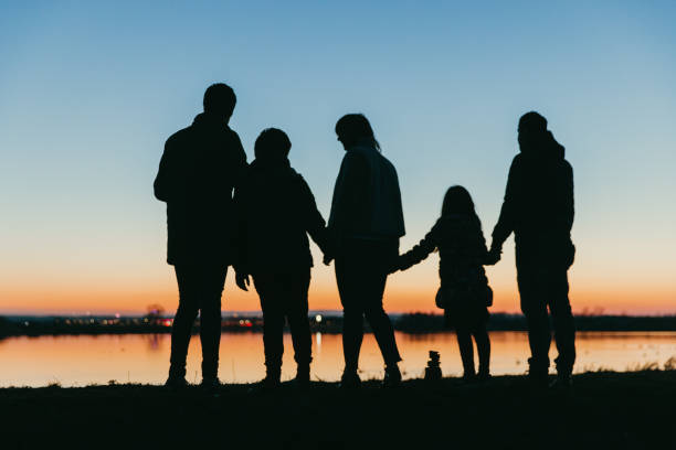 Silhouette Parents Playing With Son On Mountain Against Orange Cloudy Sky During Sunset