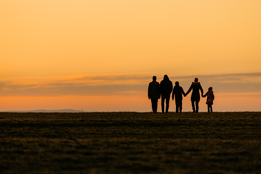 Family walking at distance on dry grassy land
