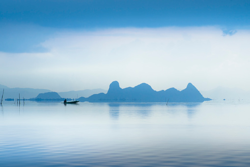 Silhouettes of Minimal fisherman at the lake in blue hour with soft light.