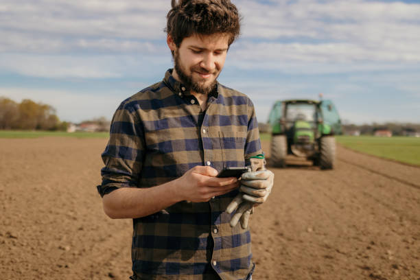 Portrait of a farmer using smartphone Portrait of smiling farmer using smartphone farmer stock pictures, royalty-free photos & images