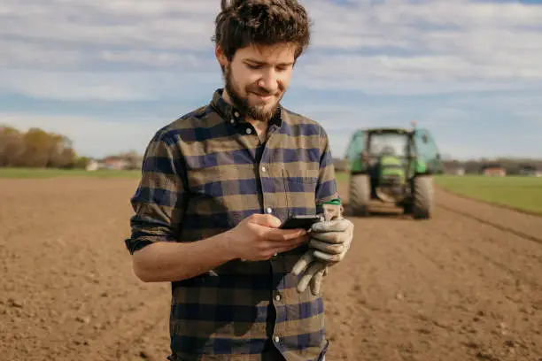 Portrait of smiling farmer using smartphone